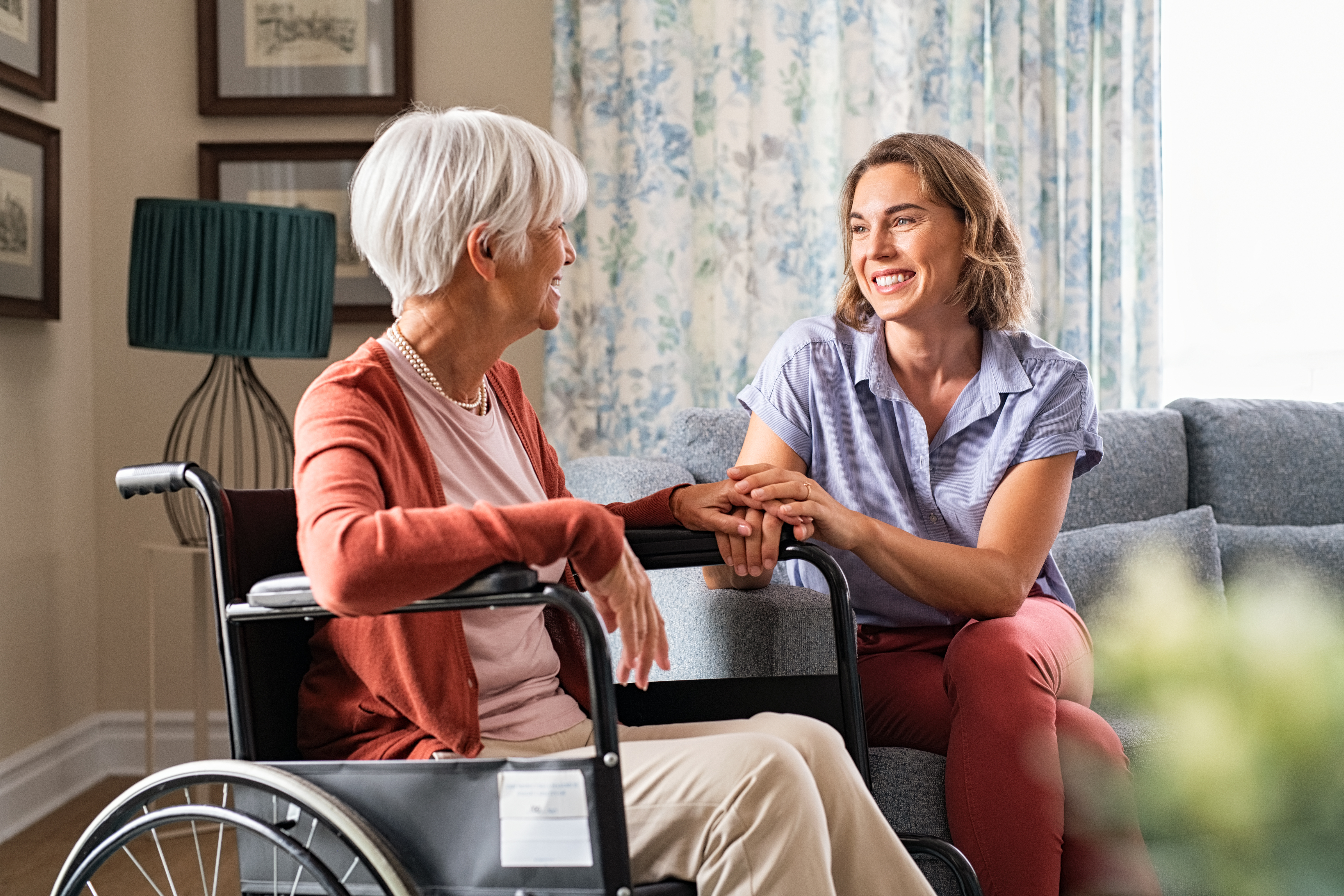 Milennial providing care for elderly woman in wheelchair.