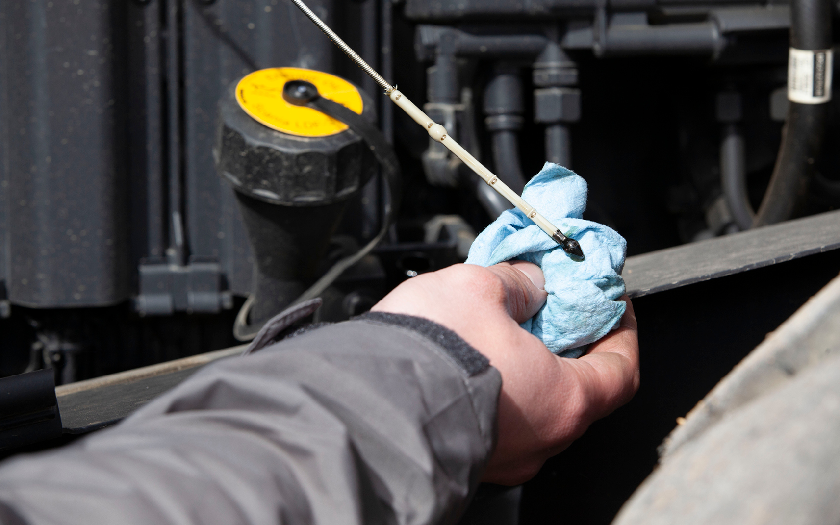 An operator checking a DEVELON wheel loader’s engine oil during the winter.