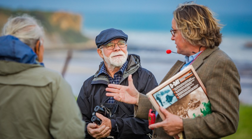 An instructor speaking to Road Scholars by the beach