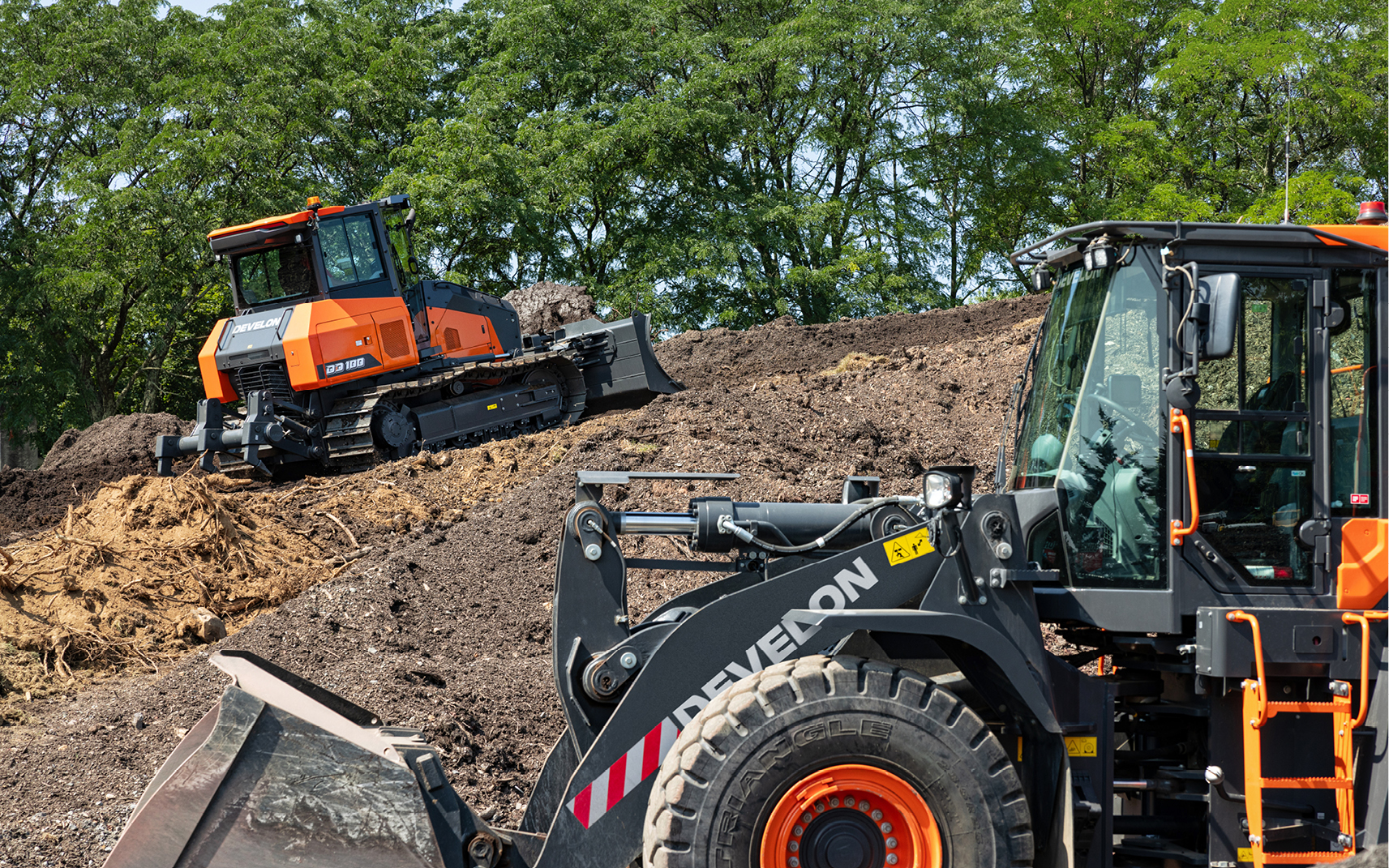 Photo of Doosan wheel loader dumping material into a Doosan articulated dump truck. 