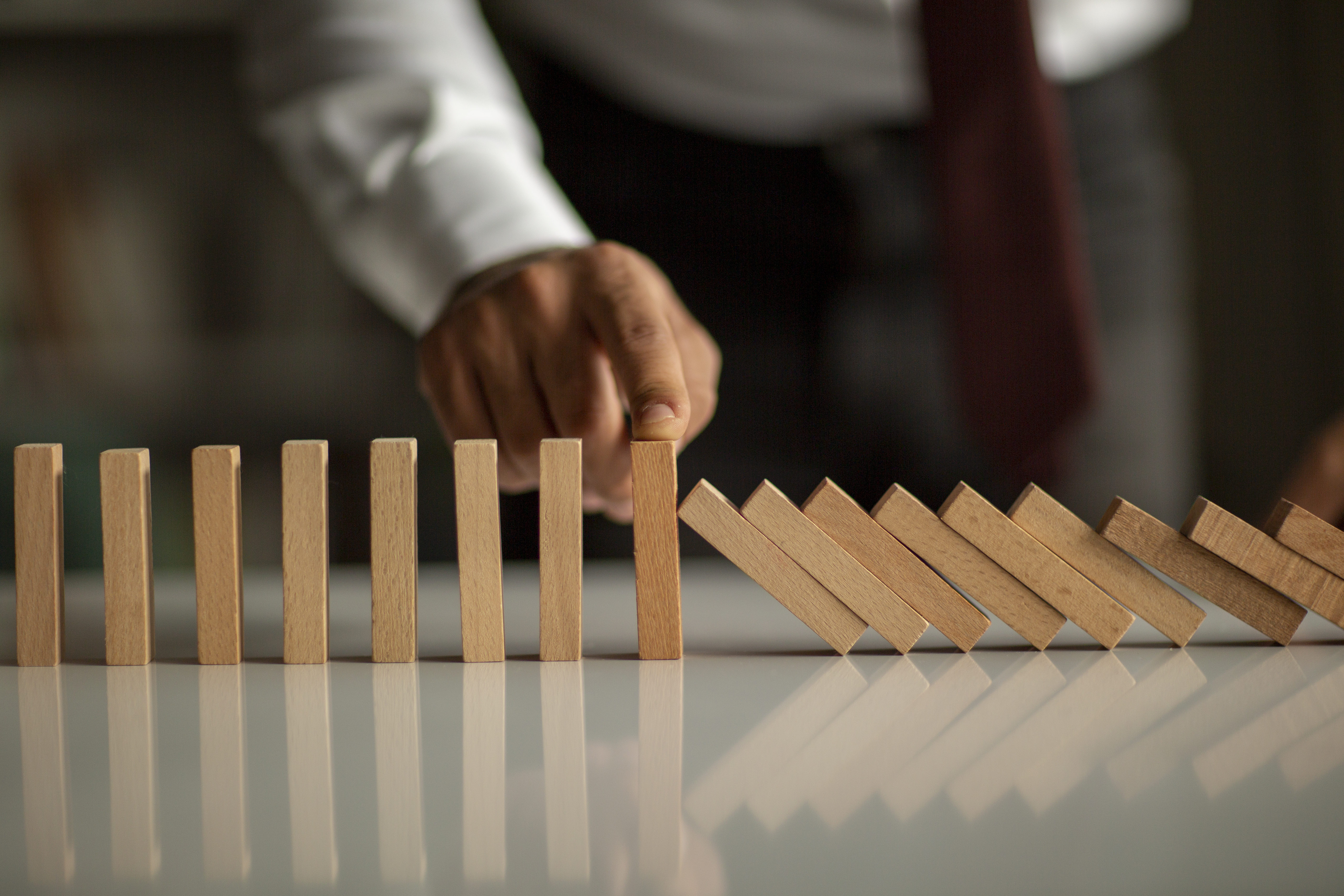 Businessman Stop Domino Effect. Risk Management and Insurance Concept