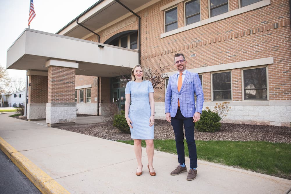 Man & Woman standing outside a school. 