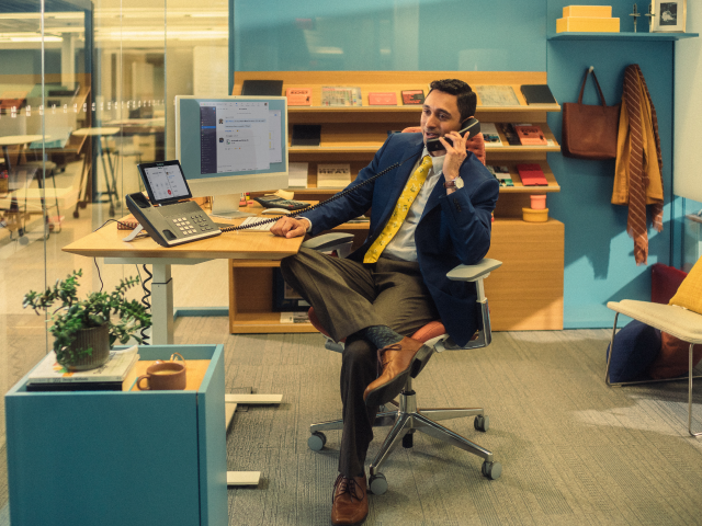 man sitting at desk on phone man sitting at desk on phone