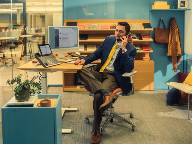 man sitting at desk on phone